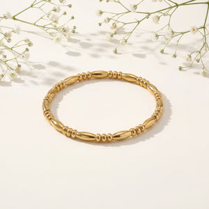 Gold bracelet on a light background with delicate white flowers