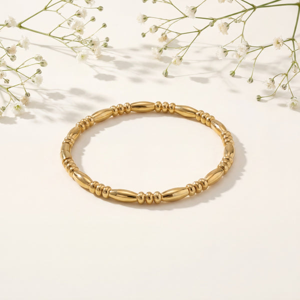 Gold bracelet on a light background with delicate white flowers