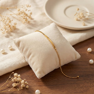 Anti-Tarnish Gold Plated Plain Celeste Bar Bracelet by House of Viya displayed on a beige cushion with pearls and dried flowers