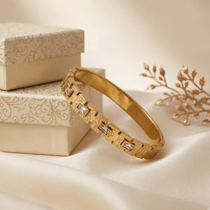 Gold bracelet with diamond accents on a beige fabric background