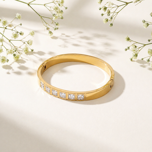 Gold bracelet with diamond accents on a light background with flowers