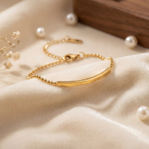 Close-up of Anti-Tarnish Gold Plated Celeste Bar Bracelet showing gold bar detail on satin fabric with pearls