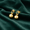 Anti-Tarnish Gold Plated Hanging Ball Earrings by House of Viya on green fabric background