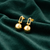 Anti-Tarnish Gold Plated Hanging Ball Earrings by House of Viya on green fabric background
