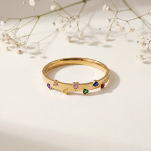 Gold ring with colorful gemstones on a light background