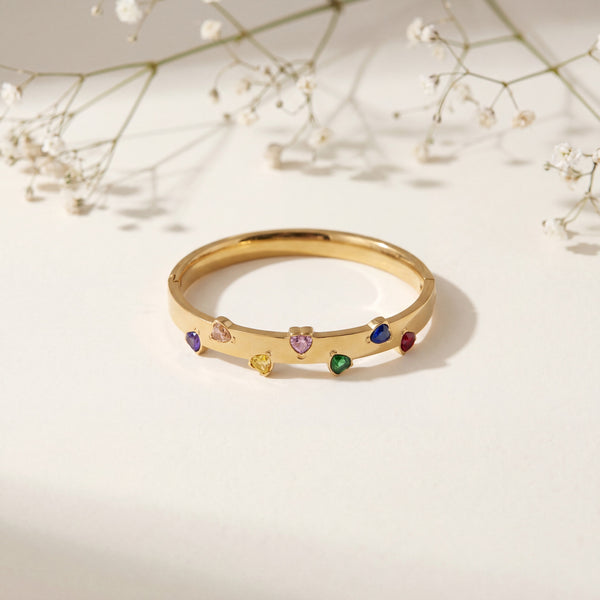 Gold ring with colorful gemstones on a light background