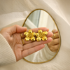 Gold plated flower stud earrings held in hand with mirror reflection - House of Viya